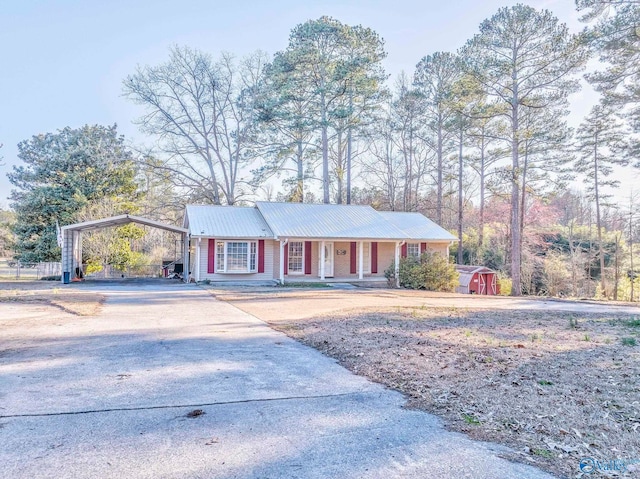 ranch-style house featuring driveway, a porch, metal roof, and a carport