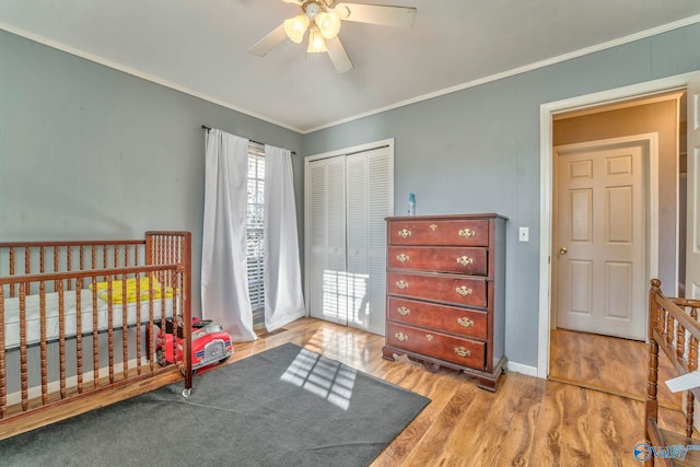 bedroom featuring light wood-style flooring, a closet, ceiling fan, and crown molding