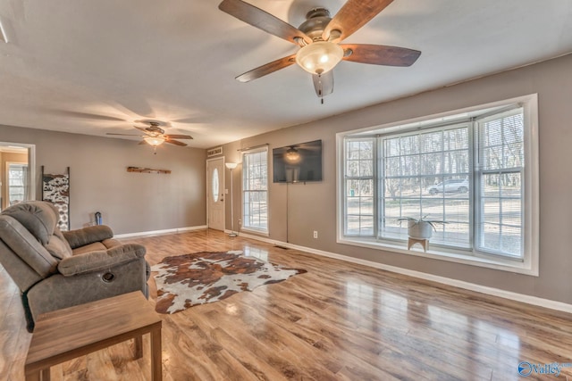 living area featuring ceiling fan, visible vents, baseboards, and wood finished floors