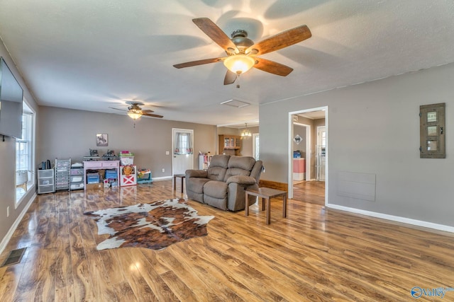 living room featuring a healthy amount of sunlight, baseboards, visible vents, and wood finished floors