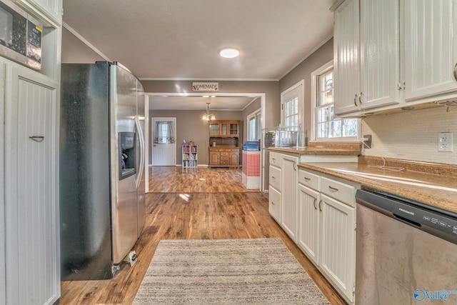 kitchen featuring light wood finished floors, light countertops, appliances with stainless steel finishes, and pendant lighting