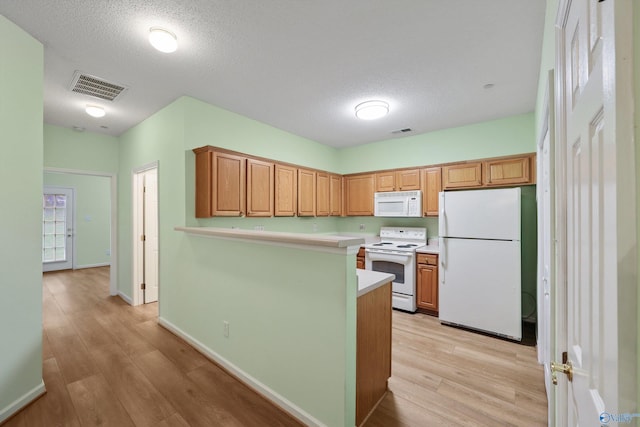 kitchen featuring a textured ceiling, light hardwood / wood-style floors, white appliances, and kitchen peninsula