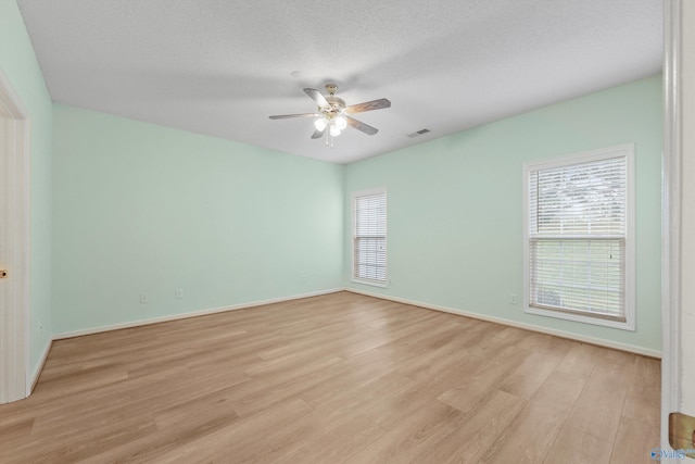 empty room with ceiling fan, light hardwood / wood-style floors, and a textured ceiling