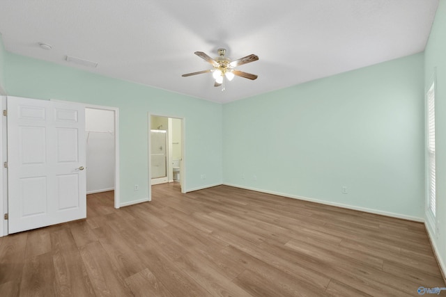 unfurnished bedroom featuring a walk in closet, ceiling fan, a closet, and light hardwood / wood-style floors