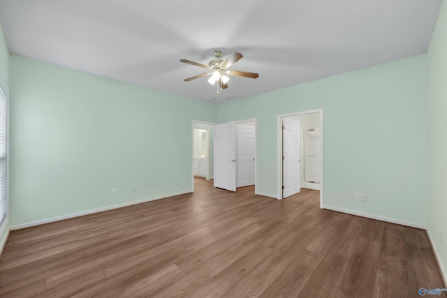 unfurnished bedroom with ceiling fan, a closet, wood-type flooring, and a spacious closet