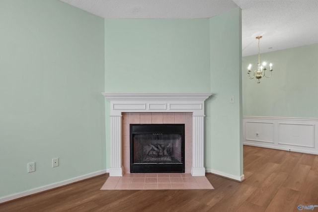 details featuring hardwood / wood-style floors, a notable chandelier, a fireplace, and a textured ceiling