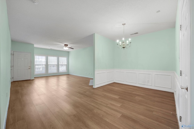 spare room with ceiling fan with notable chandelier and light hardwood / wood-style flooring