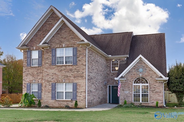 view of front facade featuring fence, a front lawn, and brick siding