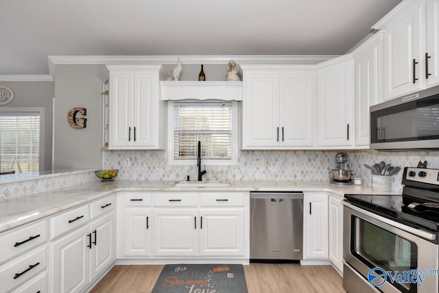 kitchen with a sink, appliances with stainless steel finishes, white cabinets, and tasteful backsplash