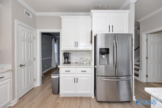 kitchen featuring crown molding, light wood-style floors, light countertops, stainless steel refrigerator with ice dispenser, and visible vents