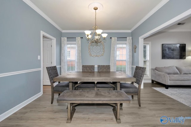 dining space with crown molding, a chandelier, a healthy amount of sunlight, and light wood-style floors