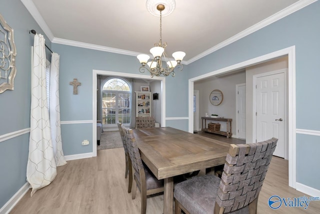 dining space featuring baseboards, ornamental molding, light wood finished floors, and a notable chandelier