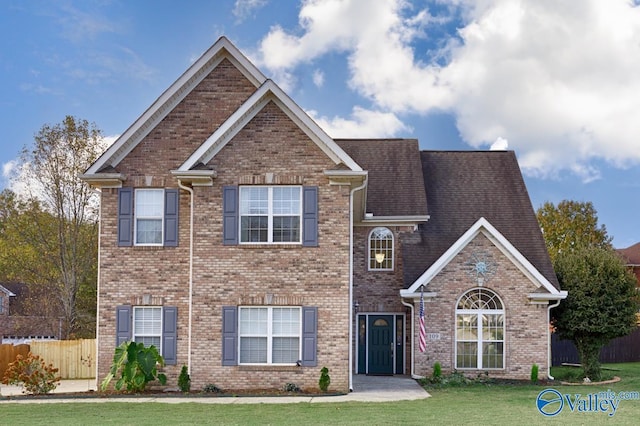 view of front of home with brick siding, fence, and a front lawn