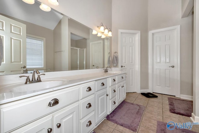 bathroom with tile patterned flooring, a sink, a shower with shower door, and double vanity