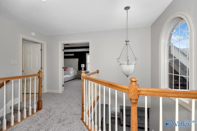corridor with baseboards, carpet flooring, and an upstairs landing