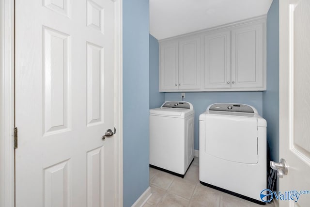 washroom with baseboards, cabinet space, light tile patterned floors, and washer and dryer