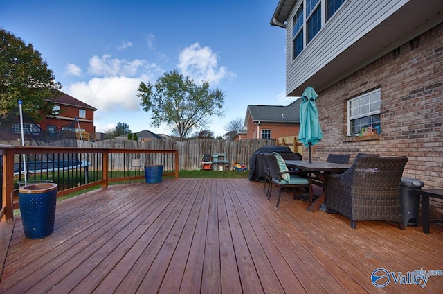 wooden terrace with outdoor dining area and a fenced backyard