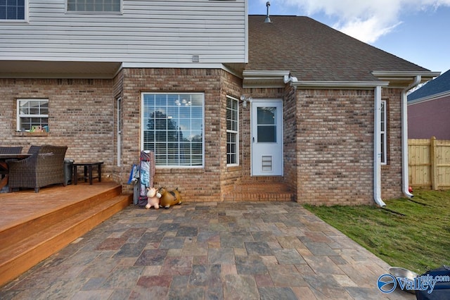 rear view of property featuring brick siding, fence, and a patio area