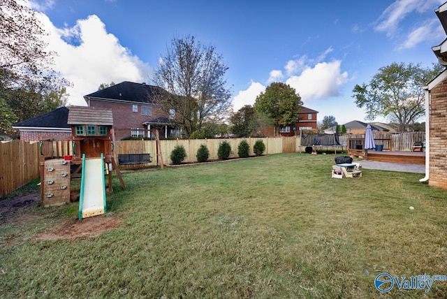 view of yard featuring a fenced backyard, a trampoline, and a playground