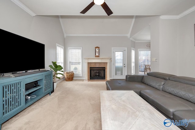 carpeted living room with crown molding, baseboards, ceiling fan, a tiled fireplace, and vaulted ceiling