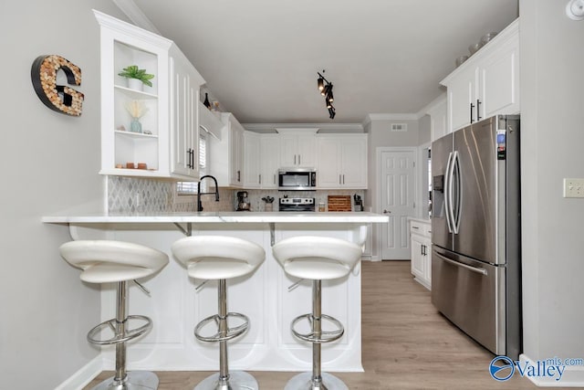 kitchen with open shelves, decorative backsplash, a peninsula, light countertops, and stainless steel appliances