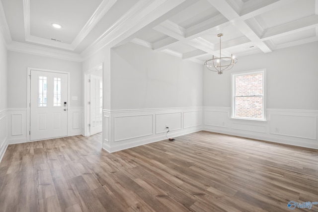 entryway with beam ceiling, coffered ceiling, a notable chandelier, light hardwood / wood-style floors, and ornamental molding