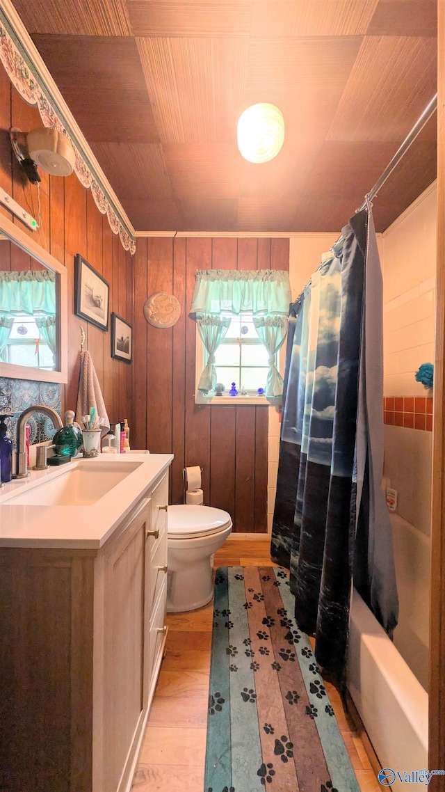 full bathroom with vanity, shower / tub combo with curtain, wood-type flooring, toilet, and wood walls