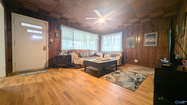 living room with hardwood / wood-style floors, ceiling fan, and wooden walls