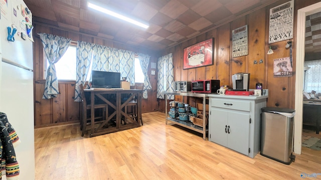 home office with light wood-type flooring, crown molding, and wooden walls