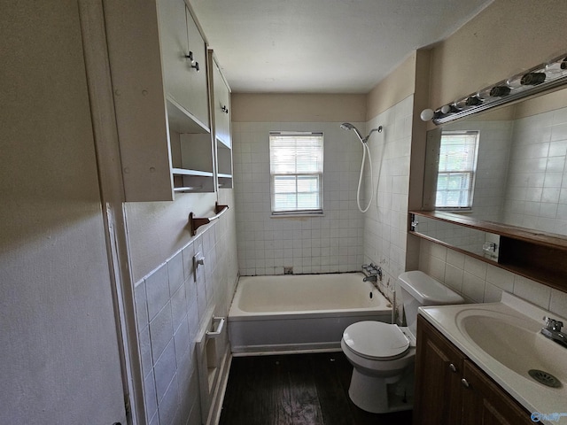 bathroom featuring tile walls, wood finished floors, vanity, toilet, and washtub / shower combination