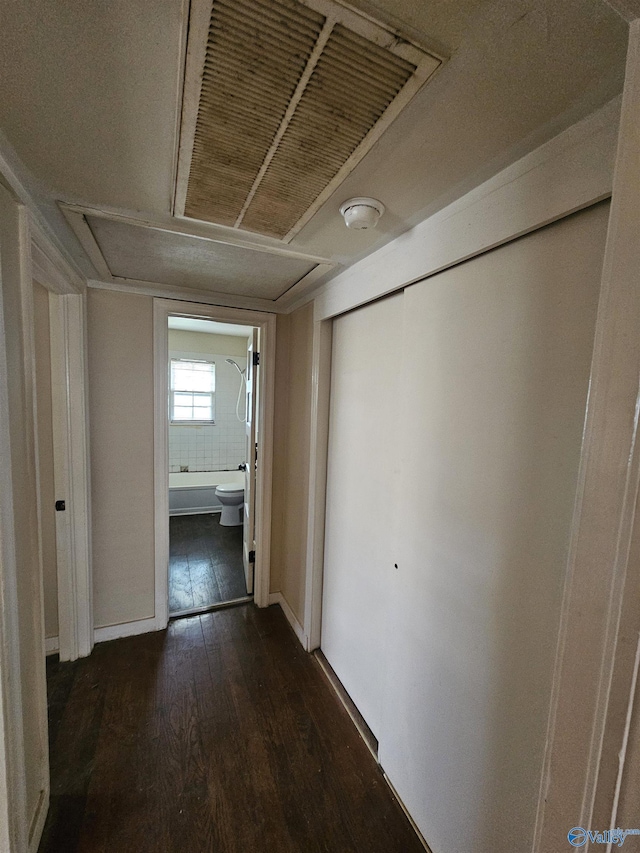 corridor with dark wood-type flooring and attic access