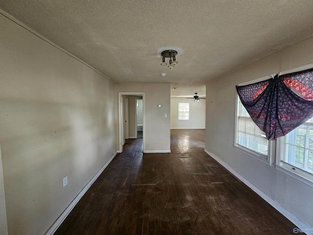 corridor with a textured ceiling, baseboards, and hardwood / wood-style flooring