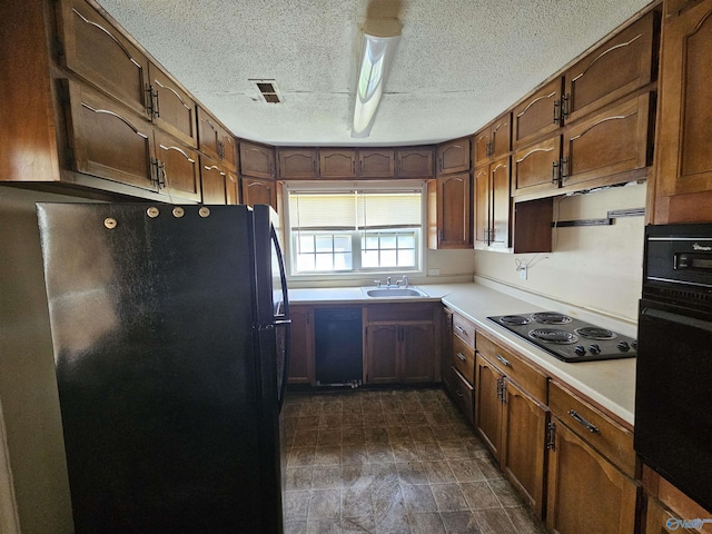 kitchen with a sink, light countertops, a textured ceiling, visible vents, and black appliances