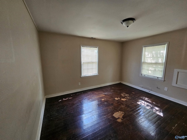spare room with baseboards and dark wood finished floors