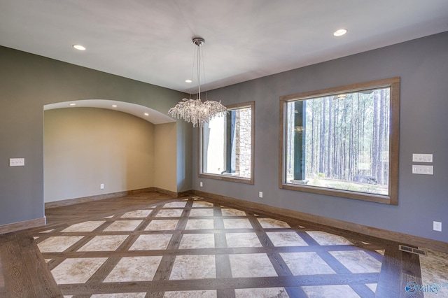 unfurnished room with recessed lighting, visible vents, arched walkways, and baseboards