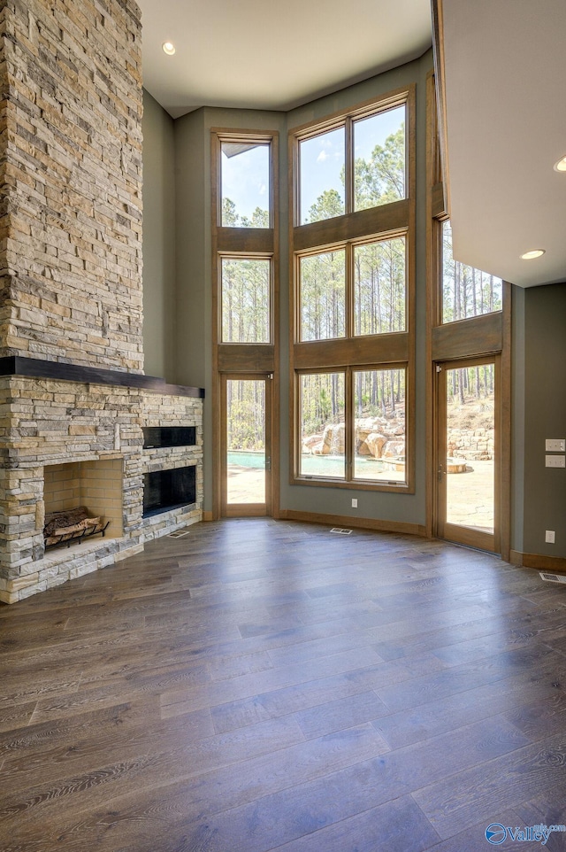 unfurnished living room featuring a fireplace, a towering ceiling, and hardwood / wood-style floors