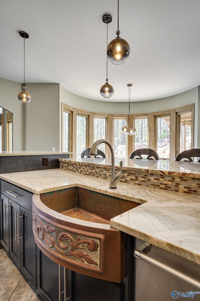 kitchen featuring backsplash, light stone countertops, light tile patterned floors, and pendant lighting