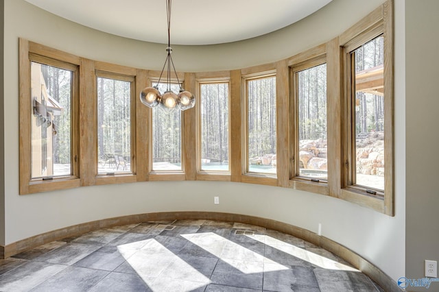 unfurnished dining area featuring a chandelier and baseboards