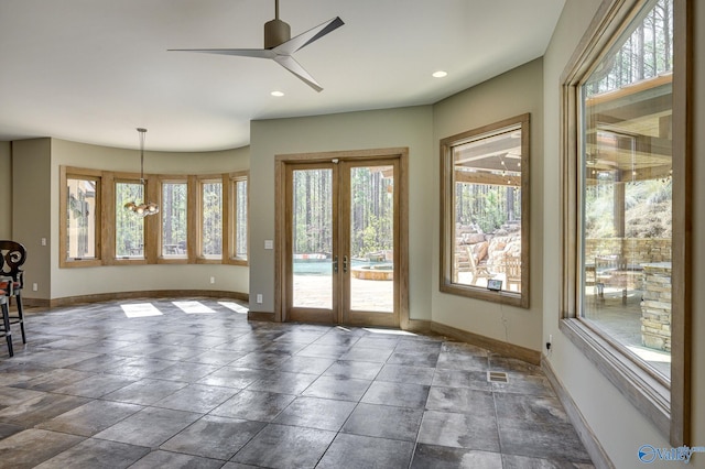 interior space with ceiling fan with notable chandelier and dark tile patterned floors