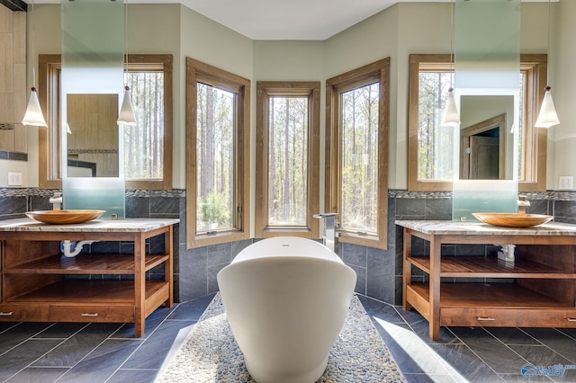 interior space with tile walls, backsplash, tile patterned floors, a tub, and vanity