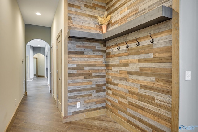 mudroom featuring arched walkways, recessed lighting, wooden walls, wood finished floors, and baseboards