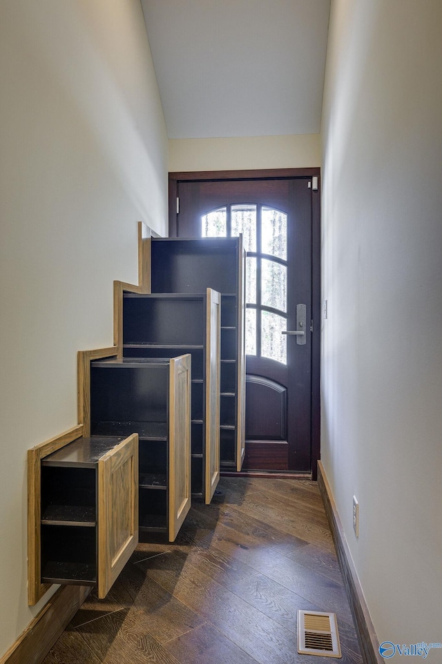 entryway with dark wood-style floors, vaulted ceiling, visible vents, and baseboards