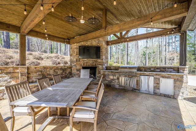 view of patio featuring a grill, an outdoor stone fireplace, and an outdoor kitchen