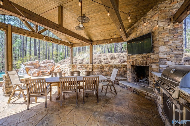 view of patio with outdoor dining space, an outdoor stone fireplace, area for grilling, and exterior kitchen