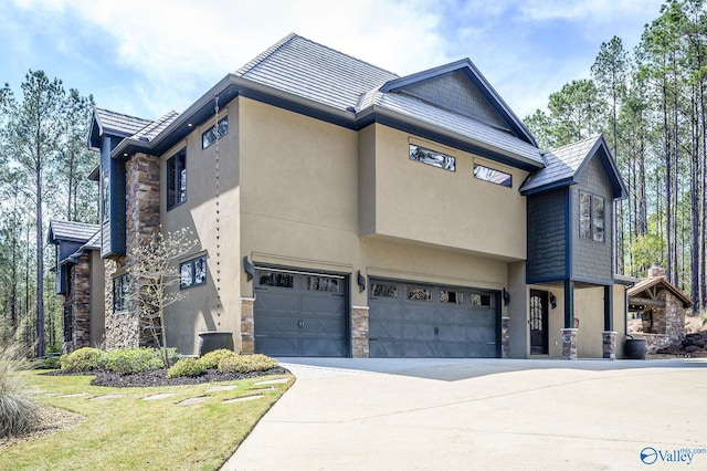 view of front of property featuring a garage, stone siding, driveway, and stucco siding