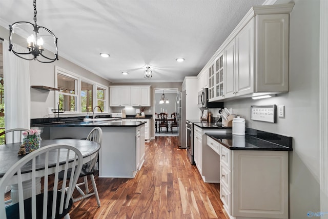 471 Oak Trl NE, Hartselle, AL 35640 - kitchen with a chandelier, crown molding, dark countertops, stainless steel appliances, and light wood-type flooring