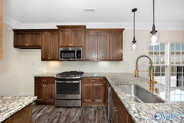 kitchen featuring light stone counters, sink, hanging light fixtures, and appliances with stainless steel finishes