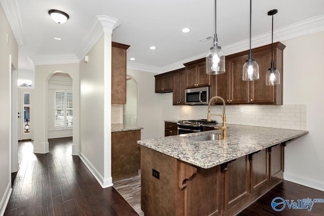 kitchen with hanging light fixtures, sink, light stone countertops, and kitchen peninsula