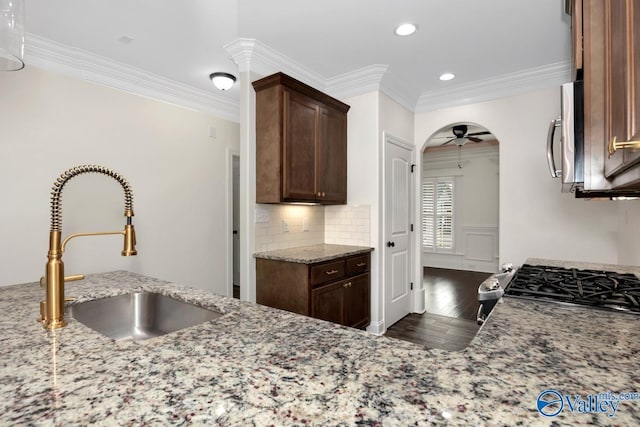 kitchen with dark hardwood / wood-style floors, sink, decorative backsplash, ceiling fan, and light stone countertops