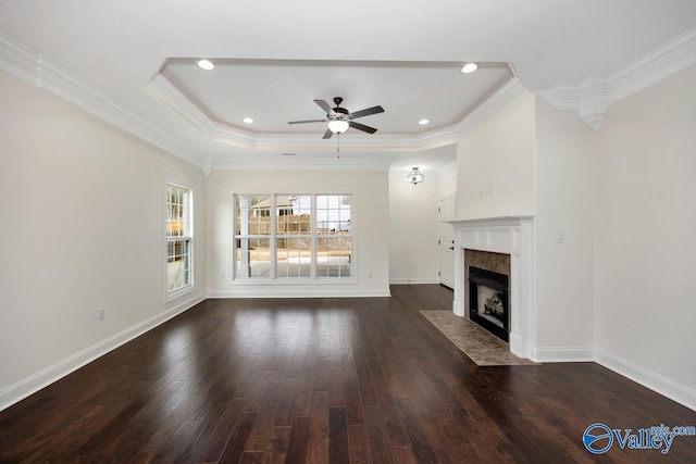 unfurnished living room featuring crown molding, dark hardwood / wood-style flooring, a raised ceiling, a tile fireplace, and ceiling fan